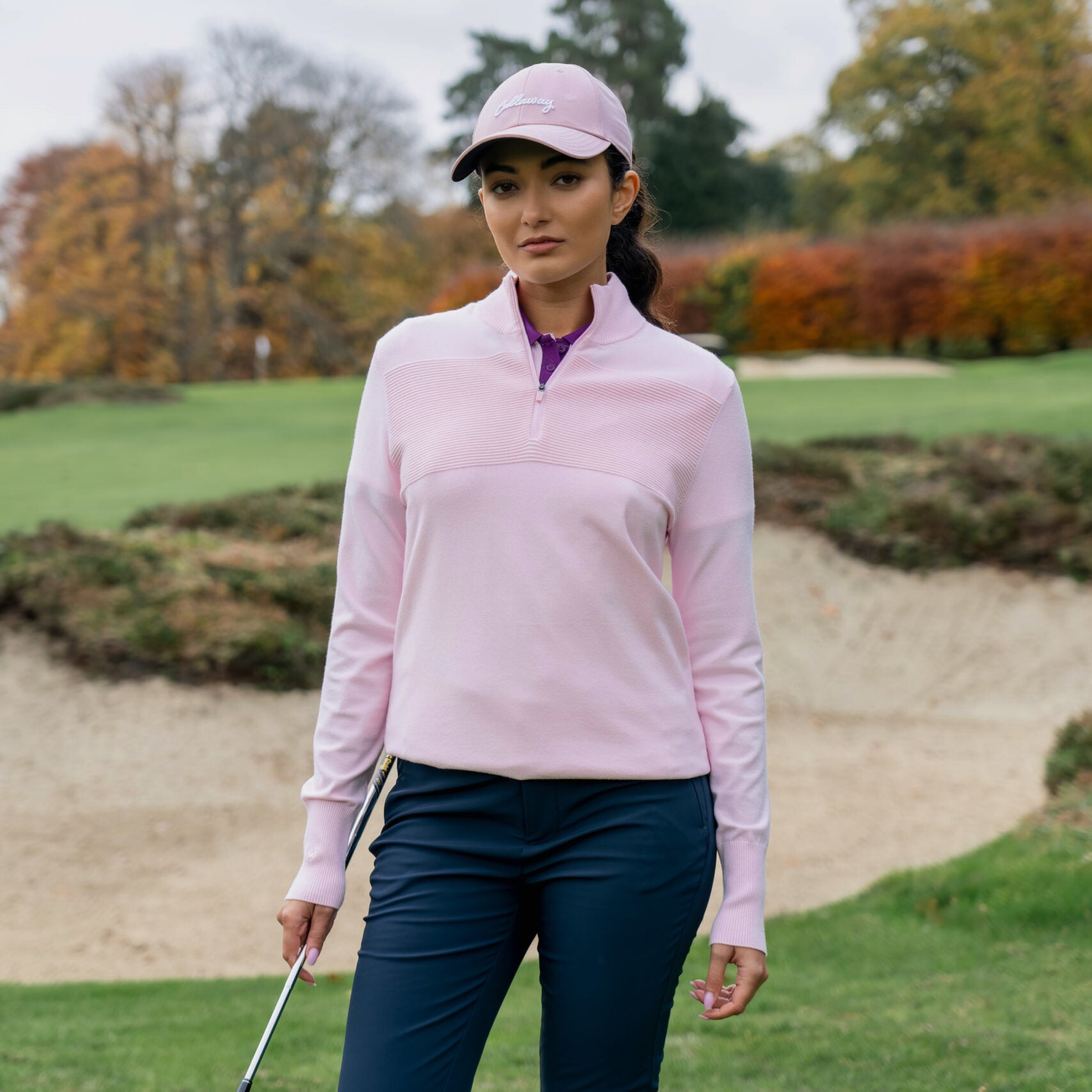 Golferin trägt den Callaway Soft Stretch Zip-Neck Pullover in Cherry Blossom auf dem Golfplatz